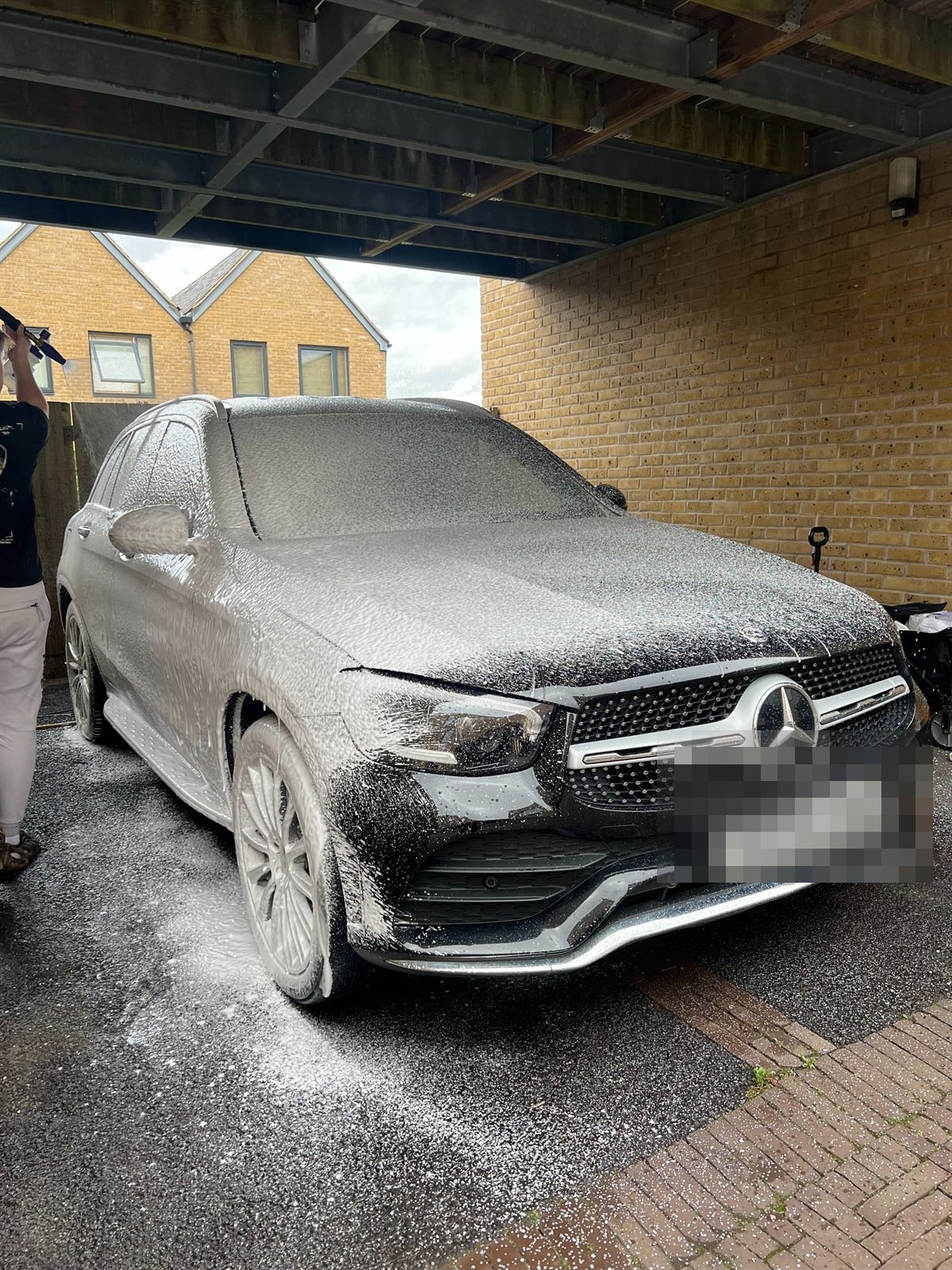 Black Mercedes GLC covered in snow foam during the pre-wash